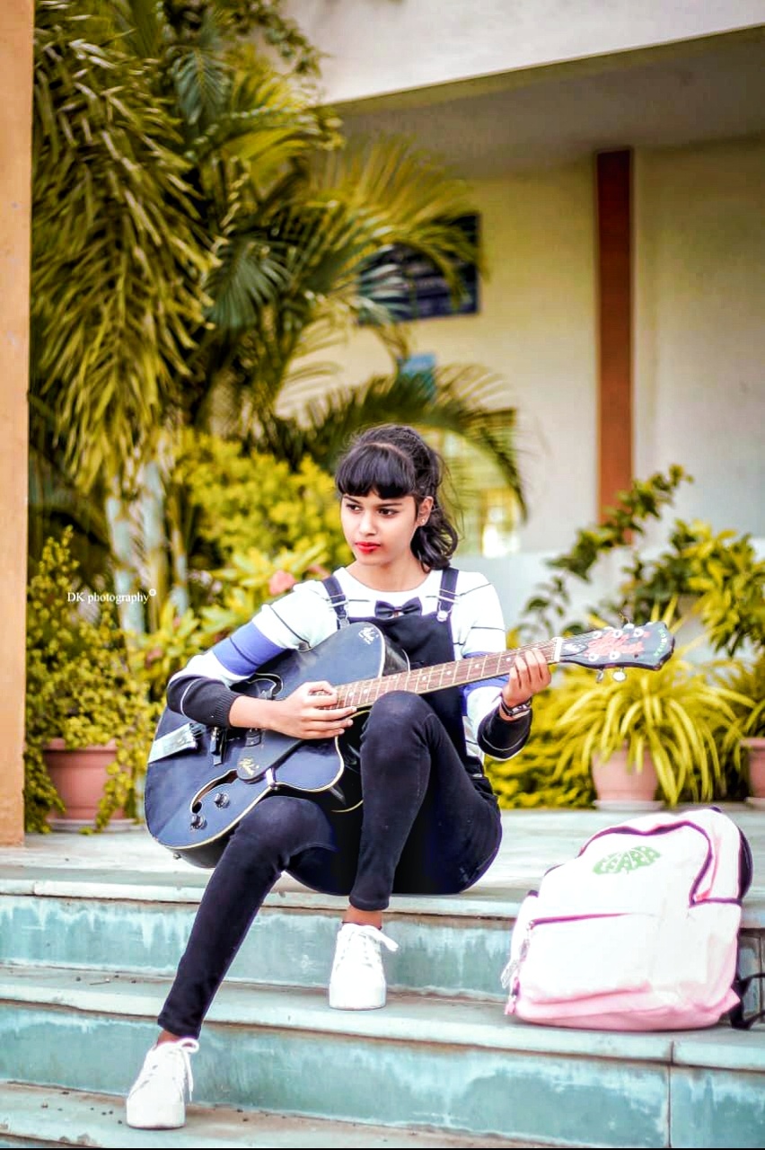 Photo of pleased fashionable female musician plays electric guitar smiles  pleasantly wears heart sha Stock Photo by wayhomestudioo